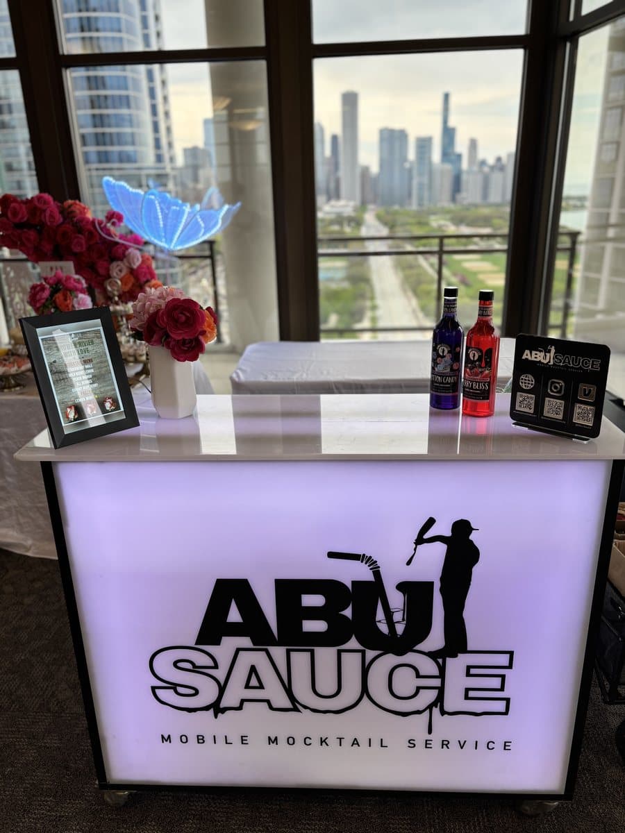 The lit Abu Sauce bar with syrup bottles and flowers, overlooking the Chicago skyline