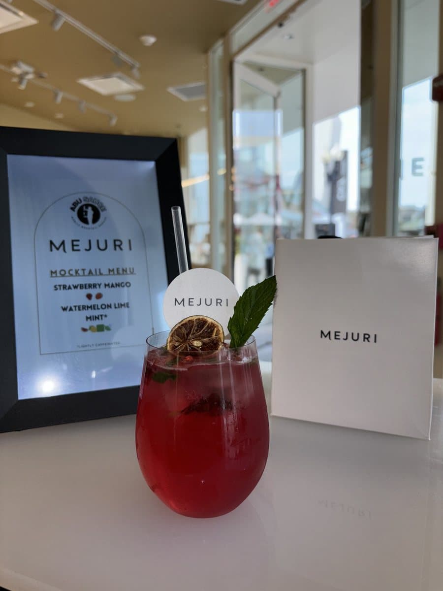 A red Abu Sauce mocktail beside a Mejuri branded mocktail menu