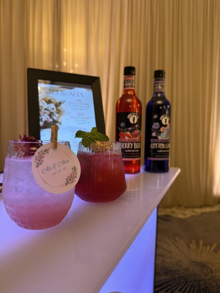 Two garnished wedding mocktails with custom 'Ali & Alia' drink tags on a lit bar