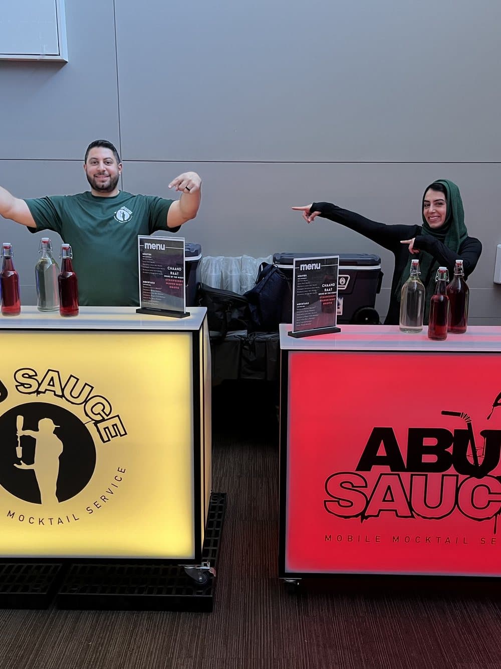 Two color-lit Abu Sauce mocktail bars with the team behind them at an event