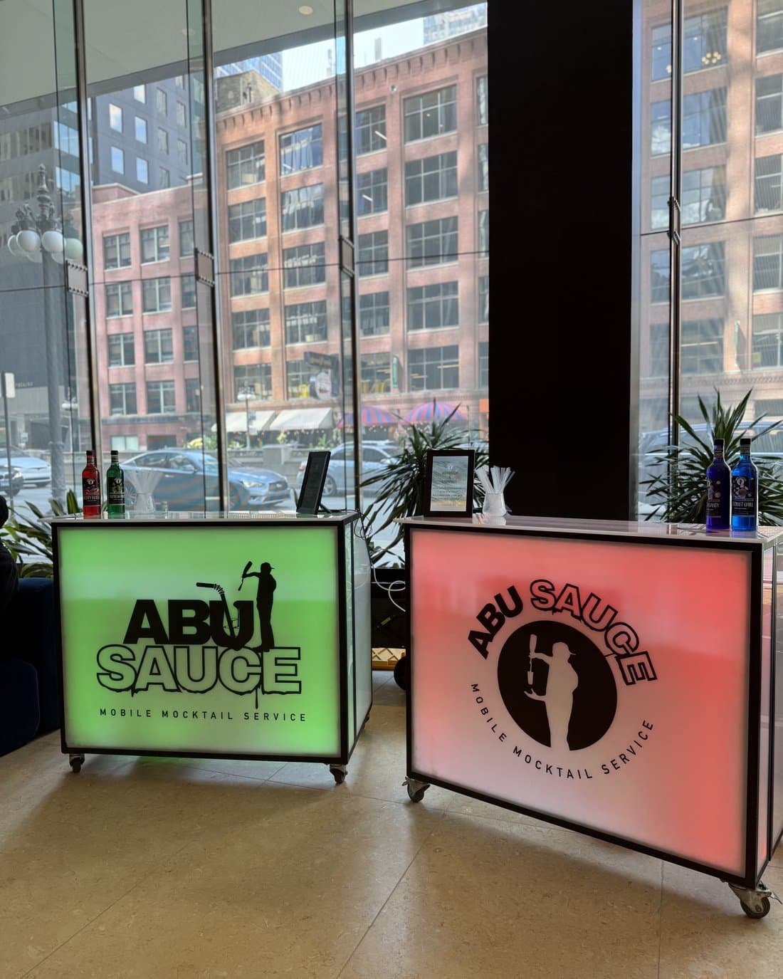 Two color-lit Abu Sauce mocktail bars set up in a downtown lobby