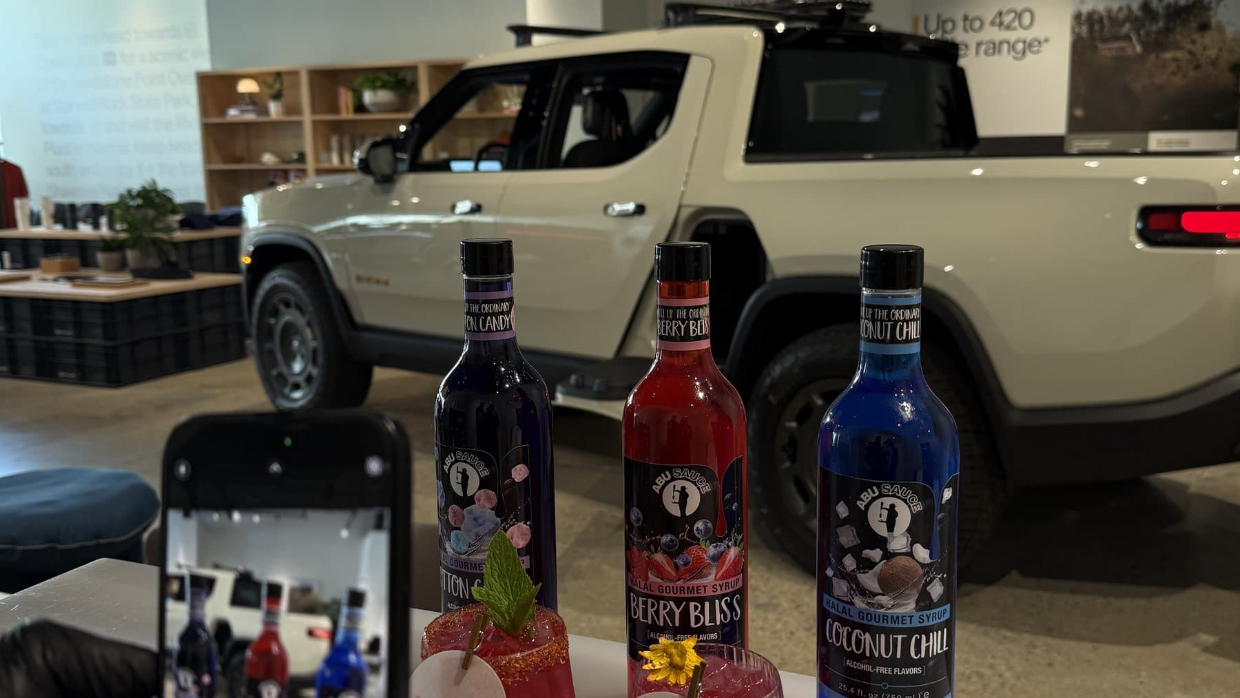 Abu Sauce syrup bottles and a mocktail on the bar at a car showroom event